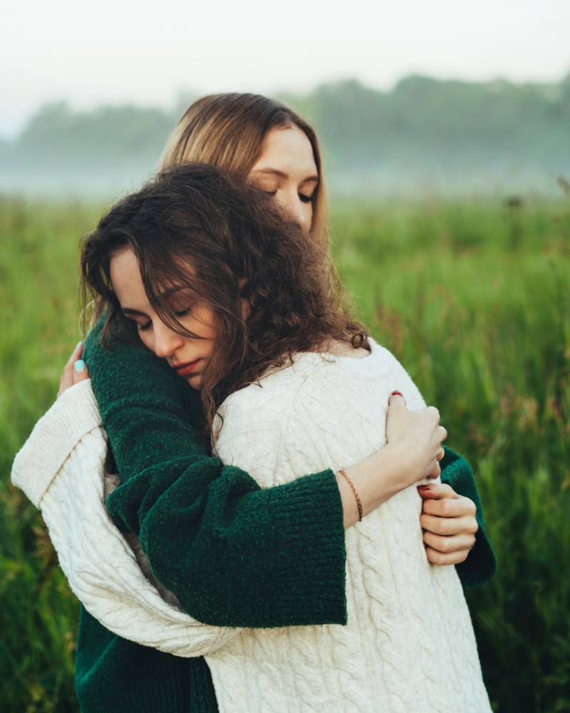 Deux jeunes femmes se prennent dans les bras dans un champ